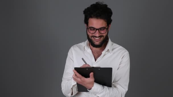 Geschäftsmann notiert im Notizblock und lächelt — Stockvideo