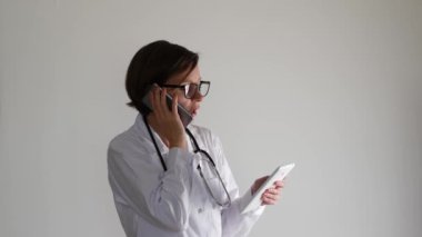 Dijital tablet kullanırken telefonda konuşan doktor