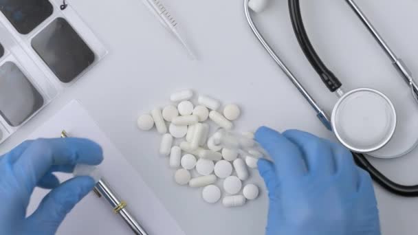 As mãos usando luvas enchem um tubo de teste de vidro de laboratório com pílulas brancas — Vídeo de Stock