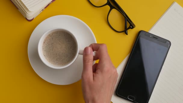 Café time.Flat mesa com telefone móvel e mão segurando xícara de café . — Vídeo de Stock