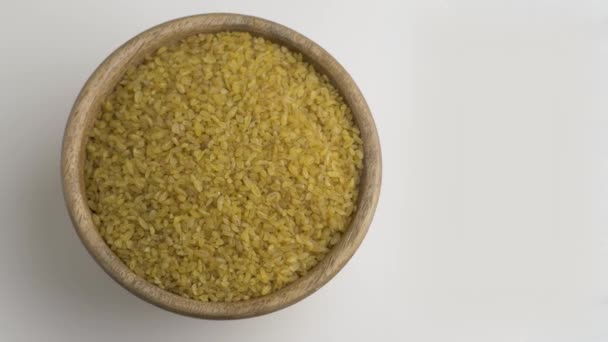 Dry bulgur wheat grains in wooden bowl. Close up — Stock Video
