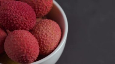 Gri bir arka plan üzerinde beyaz kase taze lychee döndürün.