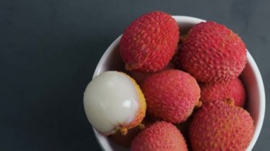 Gri bir arka plan üzerinde beyaz kase taze lychee döndürün.