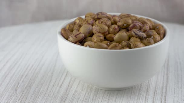 Dry pinto beans in white ceramic bowl. — Stock Video