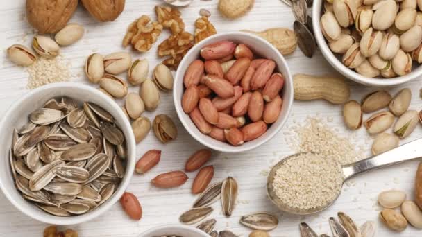 Assortment of nuts and seeds in white saucers on a white background. — Stok video