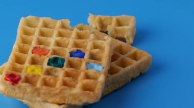 Mavi arka planda dönen tatlı renkli Belçika waffle 'ları.