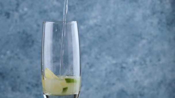 Giet sodawater in een glas met citroen op een blauwe abstracte achtergrond. — Stockvideo