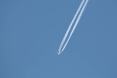 Yolcu uçak masmavi gökyüzünde uçuyor, beyaz contrail veya yoğunlaşma izleri