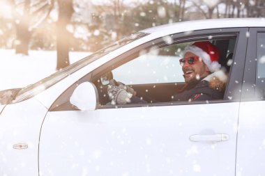 Kar ve güneşli dan zevk Noel Baba şapkası ile araç sürücüsü portresi. Tatil ve kış konsepti.