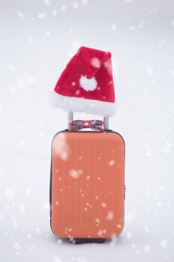 Turuncu çanta ile kar üzerinde santa şapka ve güneş gözlüğü.