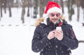 Portrét mladého muže s santa čepice a brýle na sníh den odesílání sms