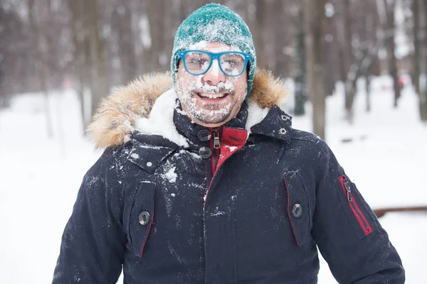 Portrait of male face covered with snow. Crazy, cheerful, funny, comic and emotions. Winter concept
