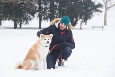 Akita köpek evde beslenen hayvan park karlı gün olan genç adam. Kış konsepti