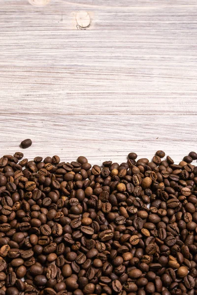 Kavrulmuş kahve çekirdekleri hafif ahşap arka plan üzerinde toplu olarak. karanlık 