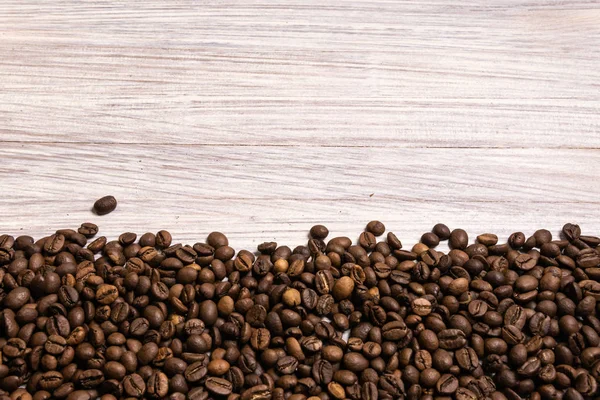 Roasted coffee beans in bulk on a light wooden background. dark