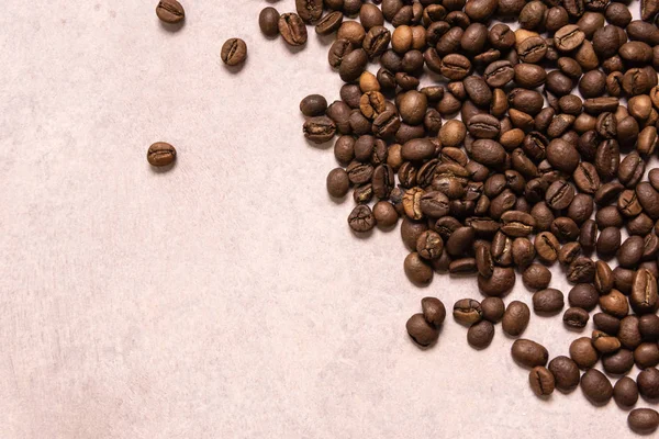 Kavrulmuş kahve çekirdekleri hafif pembe bir arka plan üzerinde toplu olarak. karanlık co