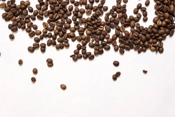 Roasted coffee beans in bulk on a light blue background. dark co