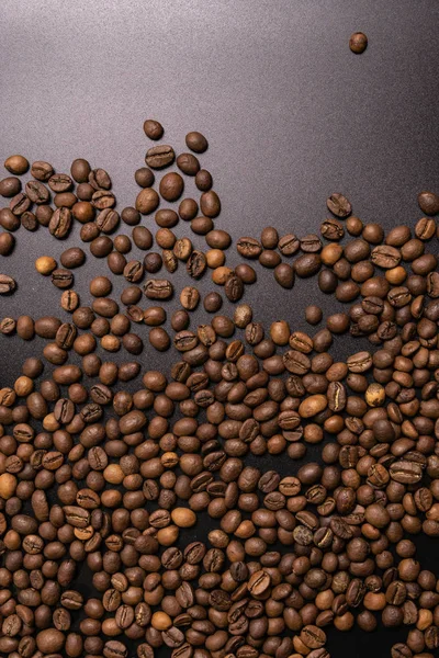 Kavrulmuş kahve çekirdekleri dökme siyah bir arka plan. koyu kahve r