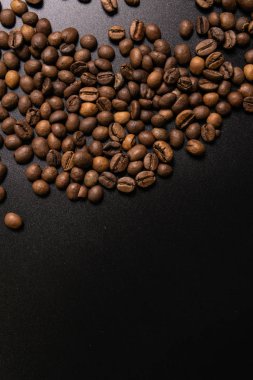 Kavrulmuş kahve çekirdekleri dökme siyah bir arka plan. koyu kahve r