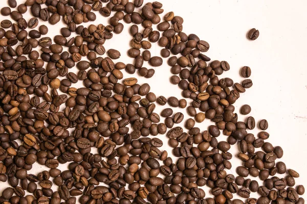 Roasted coffee beans in bulk on a light pink background