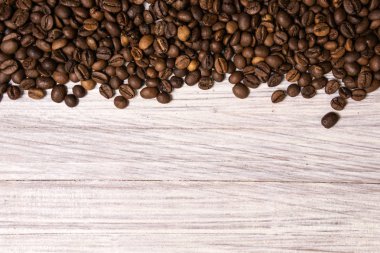 Kavrulmuş kahve çekirdekleri hafif ahşap arka plan üzerinde toplu olarak. karanlık 