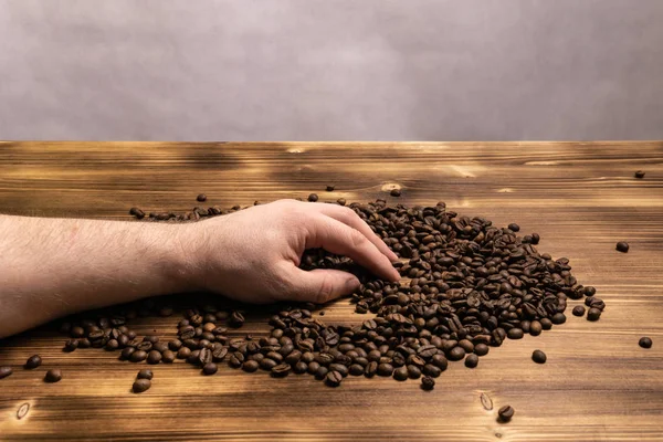 Ahşap arka plan üzerinde elinde kahve çekirdekleri