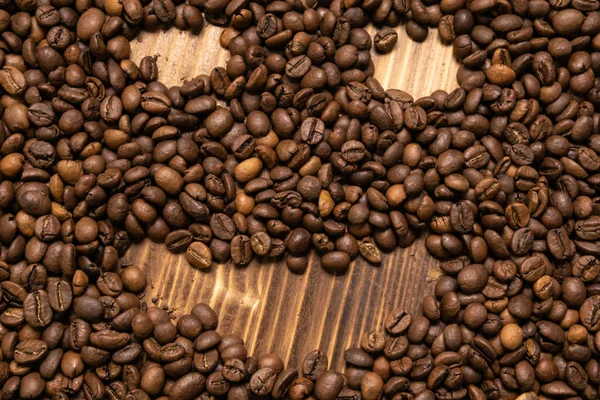 Roasted coffee beans in the form of a smiling face on a wooden b