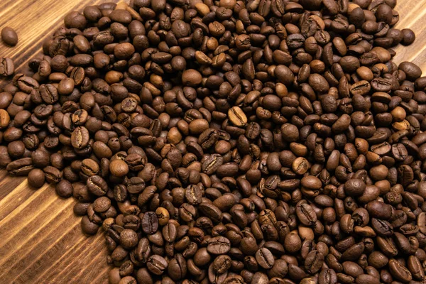 Granos de café tostados a granel sobre fondo de madera — Foto de Stock