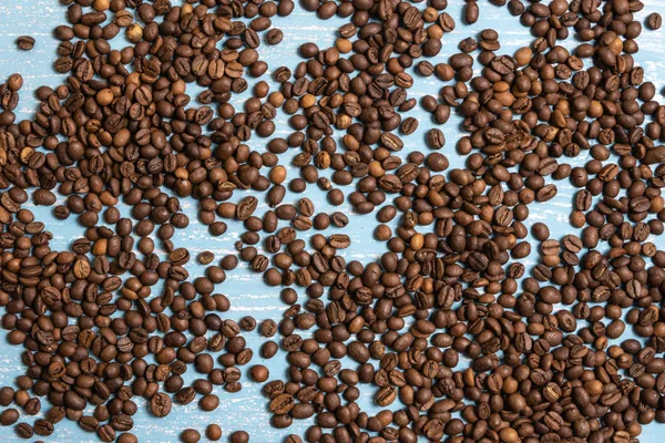 Granos de café tostados a granel sobre un fondo de madera azul — Foto de Stock