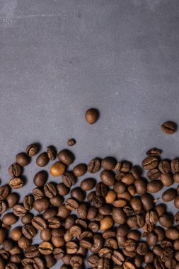 Kavrulmuş kahve çekirdekleri dökme gri beton zemin üzerine. karanlık