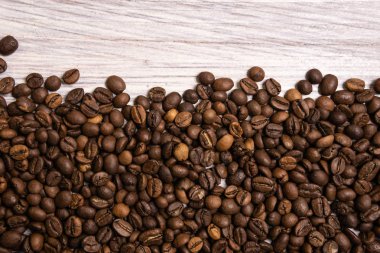 Kavrulmuş kahve çekirdekleri hafif ahşap arka plan üzerinde toplu olarak. karanlık 