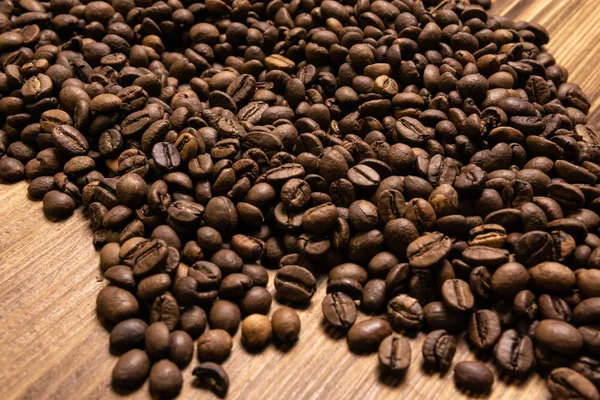Granos de café tostados a granel sobre fondo de madera — Foto de Stock
