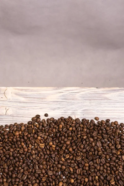Roasted coffee beans in bulk on a light wooden background. dark