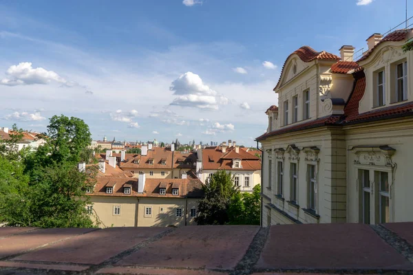 Czerwone dachy domów w Pradze z zielonych liści drzew. Widok — Zdjęcie stockowe