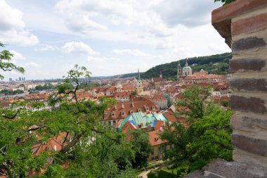 Yemyeşil ağaçların yeşil yaprakları ile Prag 'da evlerin kırmızı çatıları. Yaz aylarında şehir görünümü.