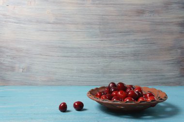 Turkuaz ahşap masada bir kil plaka kırmızı tatlı kiraz