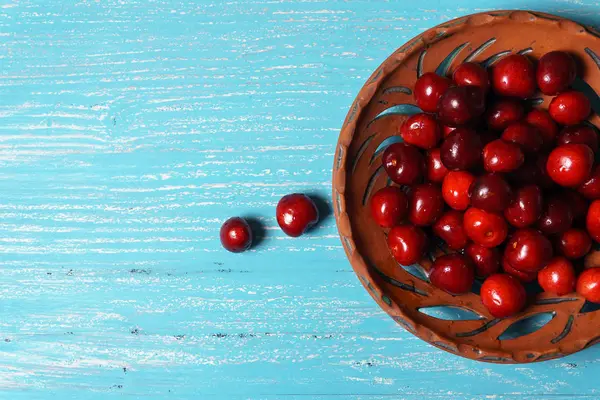 Red sweet cherry in a clay plate on a turquoise wooden table — Stock Photo, Image