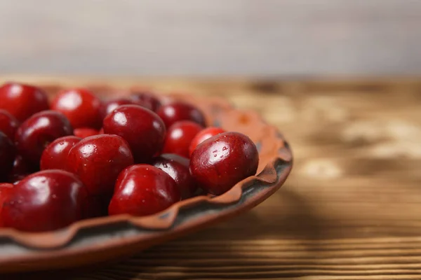 Красная вишня в глиняной тарелке на деревянном столе — стоковое фото