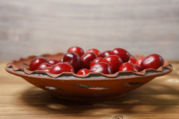Red sweet cherry in a clay plate on a wooden table — Stock Photo, Image