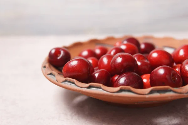 Bir krem masada bir kil plaka kırmızı tatlı kiraz