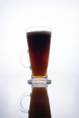 Yansıma ile beyaz bir arka plan üzerinde bir kupa koyu bira