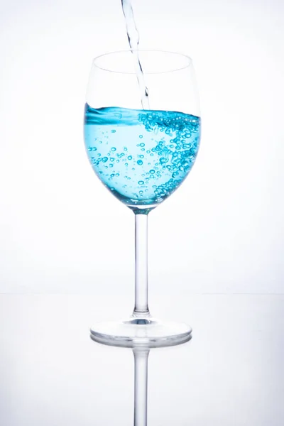 Cocktail bleu est versé dans un verre sur un fond blanc avec — Photo