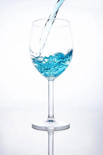 Cocktail bleu est versé dans un verre sur un fond blanc avec — Photo