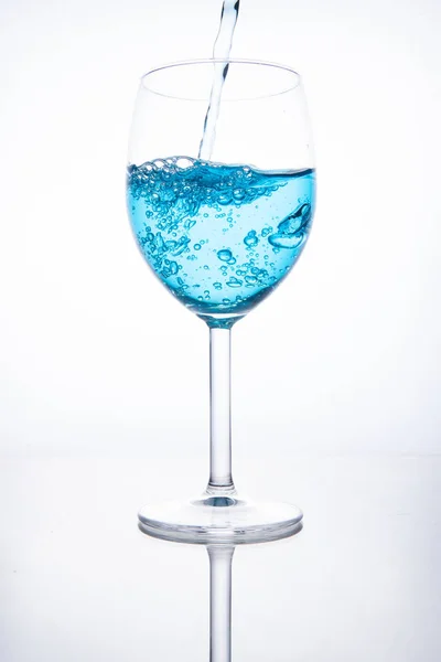 Cocktail bleu est versé dans un verre sur un fond blanc avec — Photo