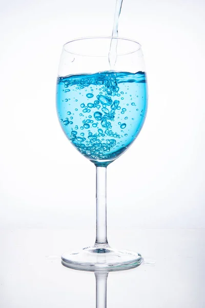 Cóctel azul se vierte en una copa sobre un fondo blanco con —  Fotos de Stock