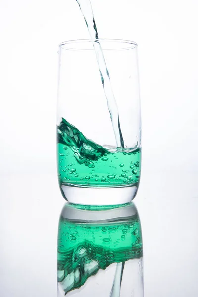 Groene cocktail wordt in een glas gegoten op een witte achtergrond met — Stockfoto