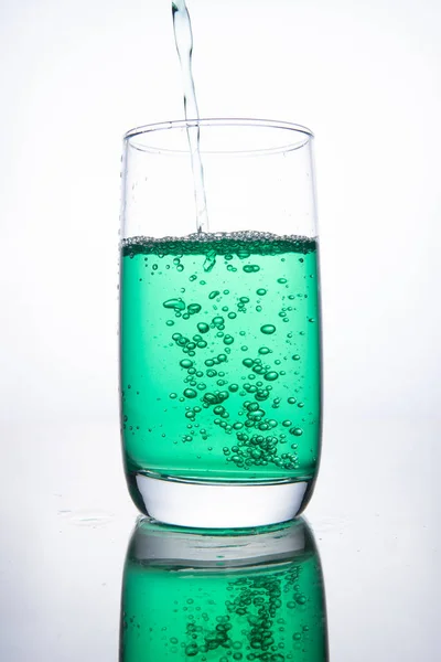 Groene cocktail wordt in een glas gegoten op een witte achtergrond met — Stockfoto