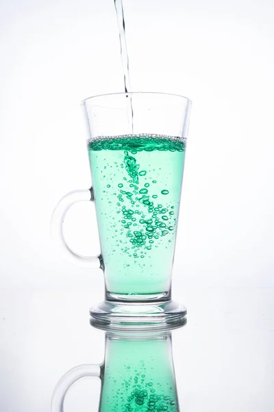 Groene cocktail wordt in een glas gegoten op een witte achtergrond met — Stockfoto