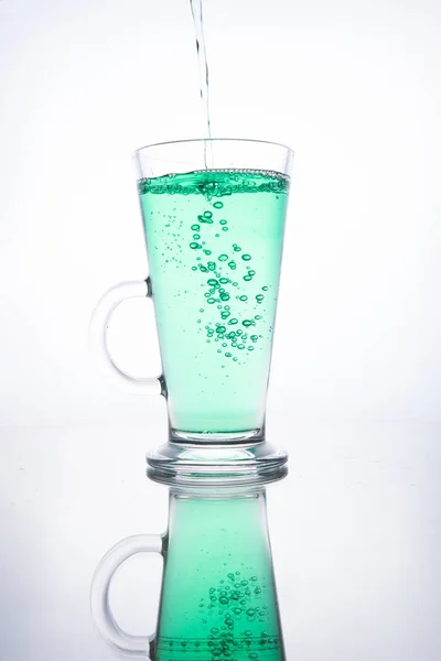 Groene cocktail wordt in een glas gegoten op een witte achtergrond met — Stockfoto