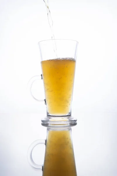 Leichtes ungefiltertes Bier, das in einen dampfenden Becher auf weißem Rücken gegossen wird — Stockfoto